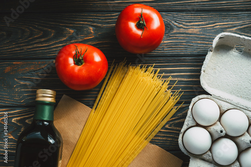 Products on the table. Pasta, olive oil, tomatoes, eggs on a wooden background. Ingredients for cooking. Coronavirus 2020, cooking at home. Close-up