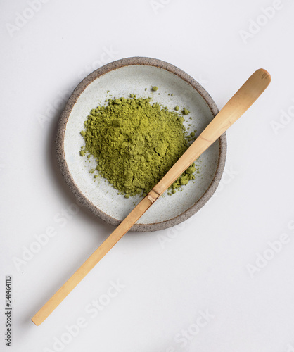 Wooden spoon on a light gray background. Matcha green tea in powder