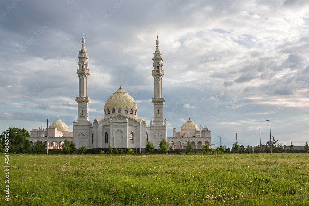 Obraz premium Beautiful white mosque in the city of Bulgar on the background of a beautiful sky with a green meadow in the foreground