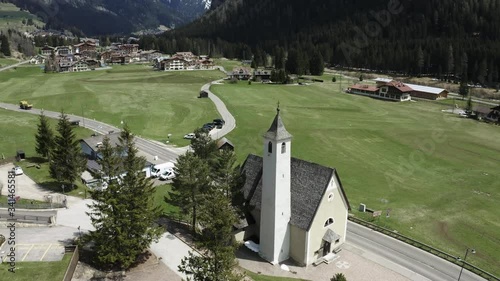 Aerial view of valley with Church of Our Lady of Carmel, green slopes of the mountains of Italy, Trentino, Fontanazzo, green meadows, Dolomites on background photo