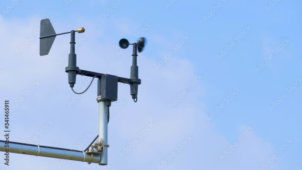Anemometer and wind vane against blue sky on windy day Anemometer and wind vane against blue sky on windy day