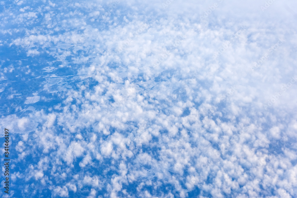 Texture of cloudy cumulus cloud fields above the earth in blue tone.