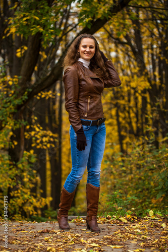 Full body portrait of a young beautiful woman in blue jeans in autumn park