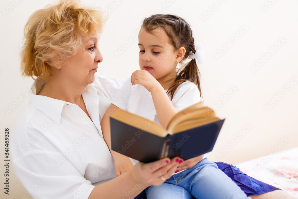 Grandmother reading a tale to her baby granddaughter. Family Reading Leisure. Quality Time. Happy Family having fun playing at home. Grandmother reading a tale to her baby granddaughter. Family Reading Leisure. Quality Time. Happy Family having fun playing at home.