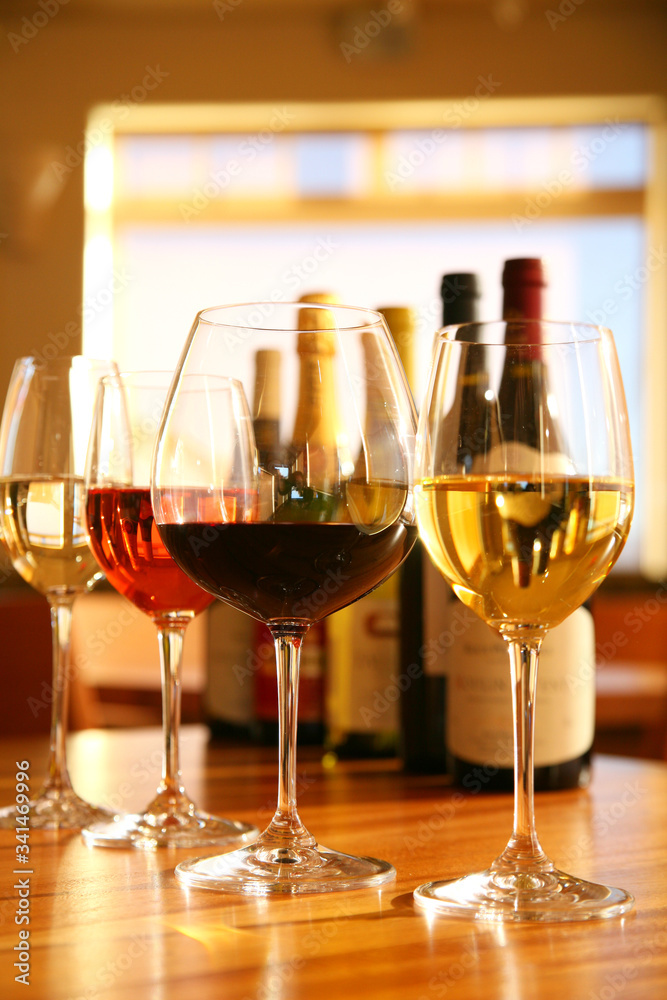 Four Glass of Wine and Bottles Sitting on Bar with Warm Natural  Light Flooding in