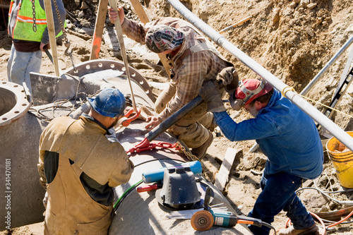 Construction Crew Laying Large Water and Sewer Pipes Using Hoist