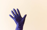 female hands with latex gloves waves by her hand, hello. Orange background. copy space. Concept of protection and care.
