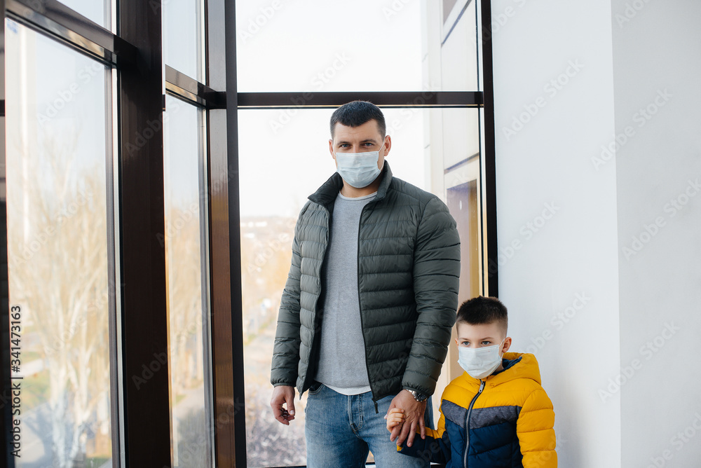 A father with his child stands in a mask during the quarantine. Pandemic, coronavirus