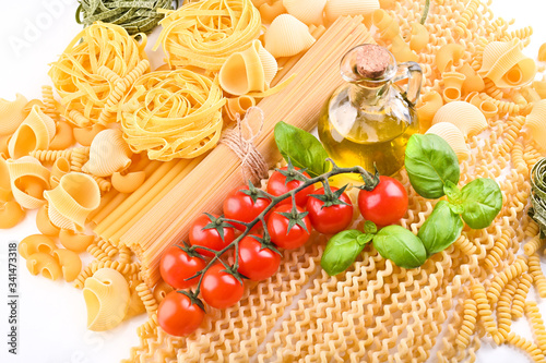 Pasta with fresh tomatoes, basil and olive oil on light shabby rustic background, top view, border. Pasta with ingredients for cooking. Italian food.