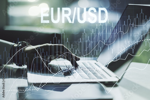 Creative concept of EURO USD financial chart illustration and hands typing on laptop on background. Trading and currency concept. Multiexposure