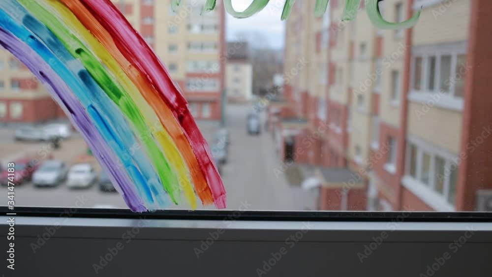 Social media campaign to prevent the covid-19 coronavirus pandemic. Drawing of a rainbow on a window during home quarantine. The sign on the window reads: Social media campaign to prevent the covid-19 coronavirus pandemic. Drawing of a rainbow on a window during home quarantine. The sign on the window reads: