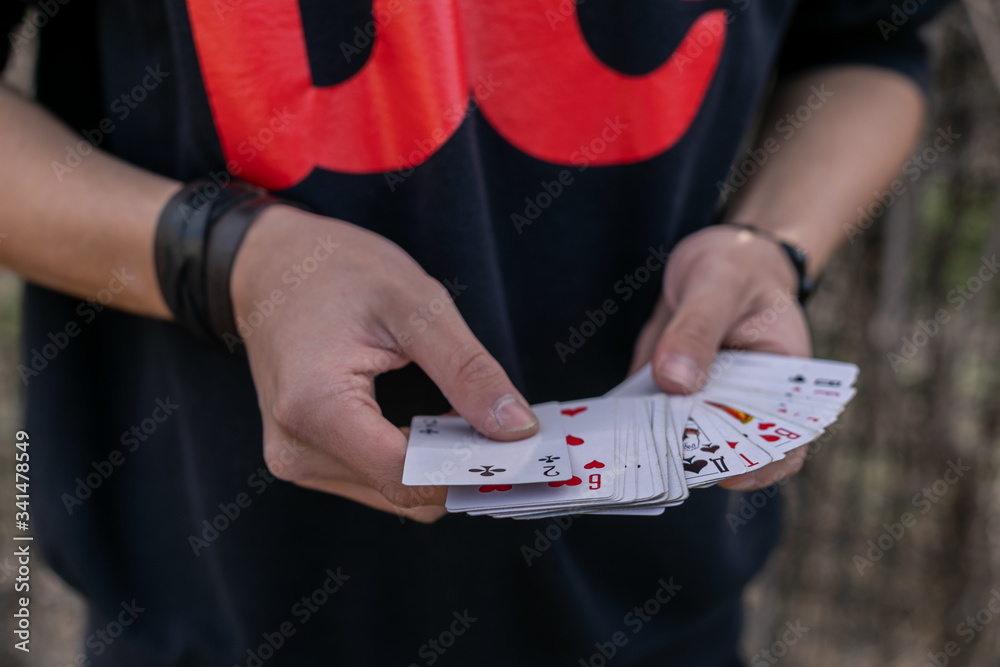 teenager holding a bunch of cards showing a magic card trick
