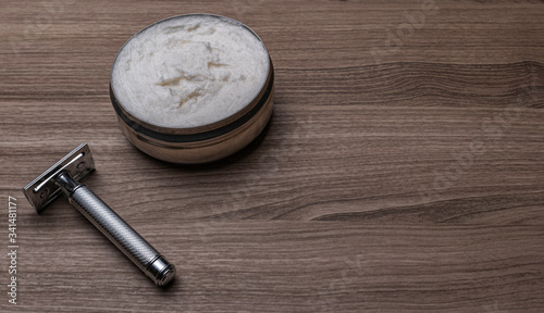 Artisan shaving cream and security razor on wooden background