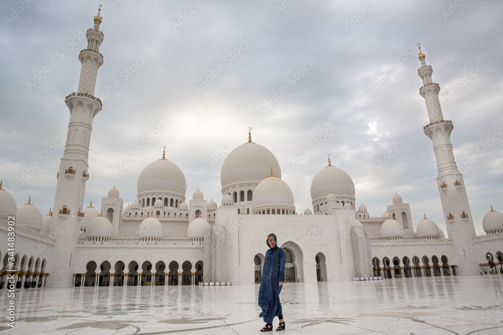 Fototapeta premium a girl in front of a mosque in Abu Dhabi under a palm tree UAE
