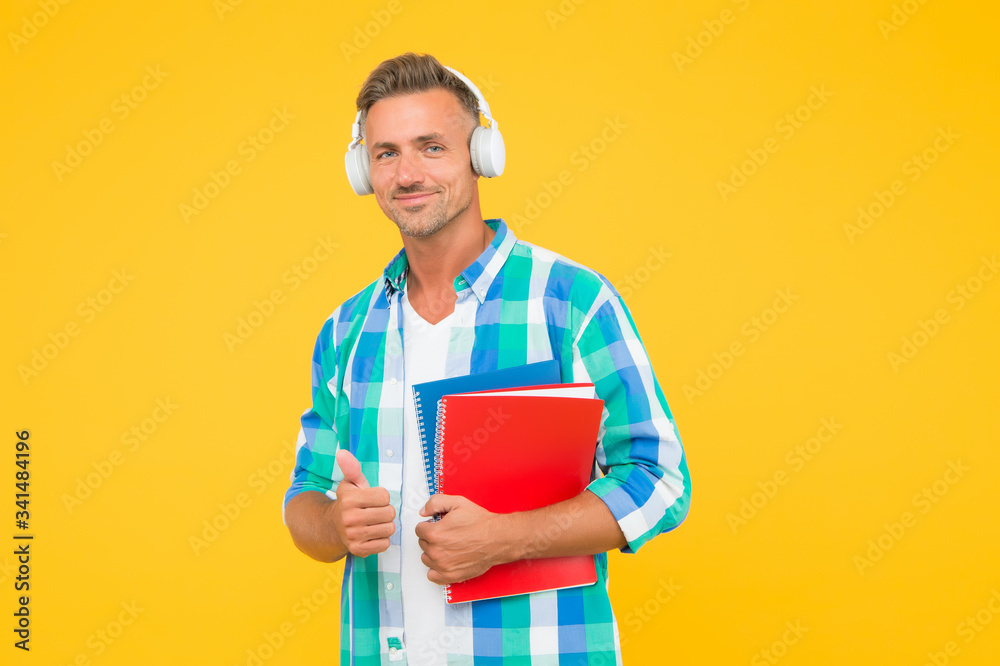 adult student hold notebook. man with folder in headphones. online education. man hold book for notes while listen ebook. lets write in notepad. handsome school or university teacher. thumb up adult student hold notebook. man with folder in headphones. online education. man hold book for notes while listen ebook. lets write in notepad. handsome school or university teacher. thumb up