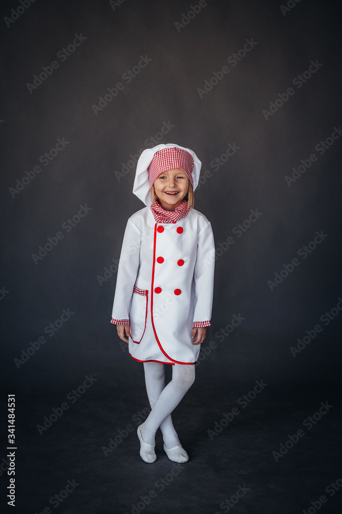 little girl in a white chef uniform on a dark background little girl in a white chef uniform on a dark background