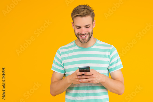Texting SMS message. Happy guy send sms via smartphone yellow background. Sms messaging. Short message service. New technology. Mobile lifestyle. Modern life. Trusted SMS delivery © be free