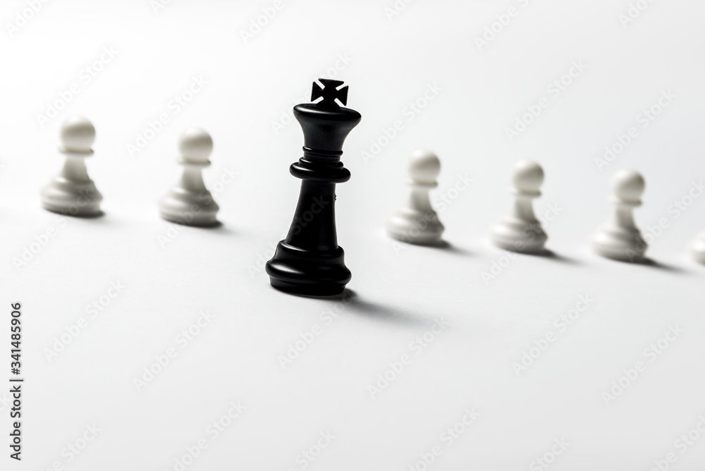 chess king is standing against white pawns. Symbol of leadership and confrontation. Horizontal frame chess king is standing against white pawns. Symbol of leadership and confrontation. Horizontal frame