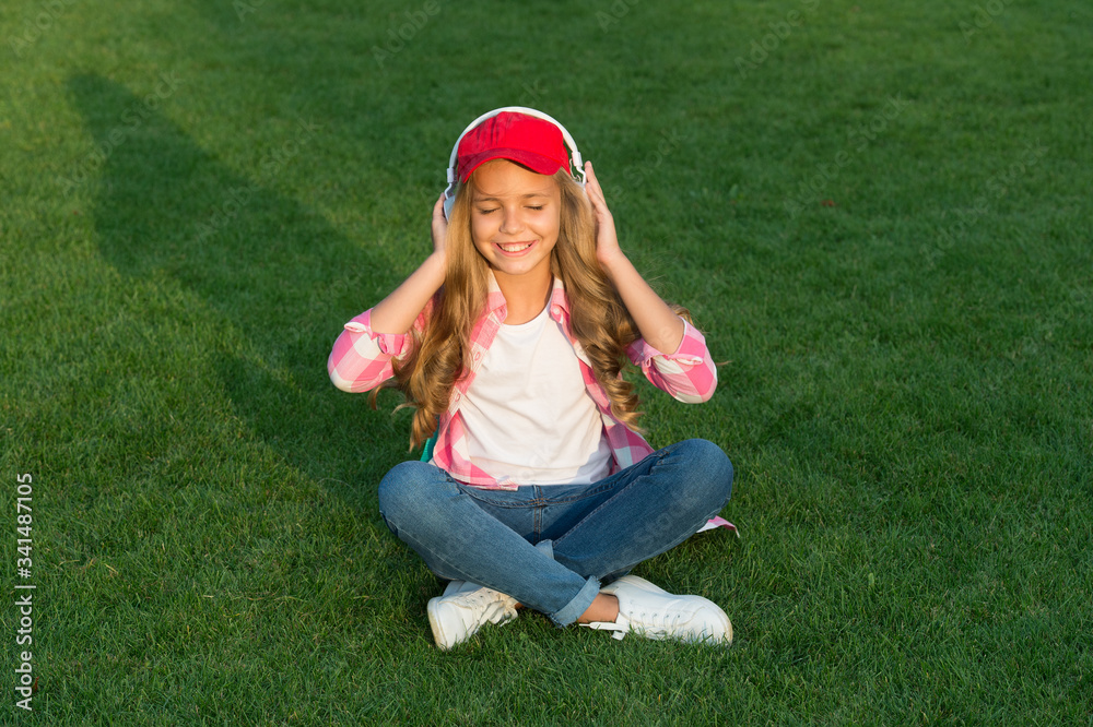 Relaxing sound. Happy child listen to sound track outdoors. Small girl enjoy music playing in earphones. Hi-Fi stereo sound. Sound and music technology. Modern life. New way to chill out