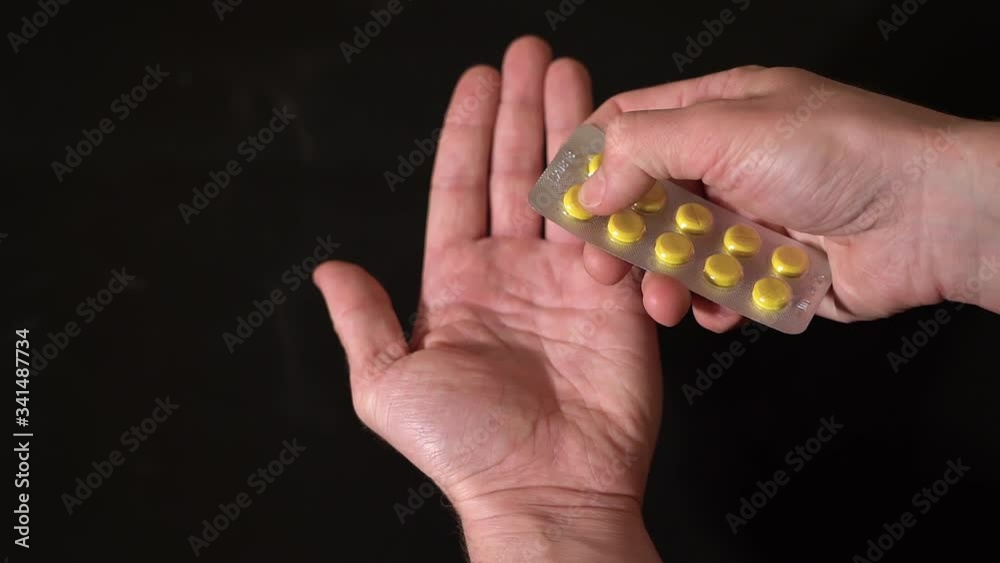 On black background in slow motion out of the blister squeezed, pills in hand On black background in slow motion out of the blister squeezed, pills in hand