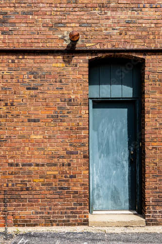 Blue door with threshold and arched passthrough set in lovely yellow and brown brick wall in ally photo