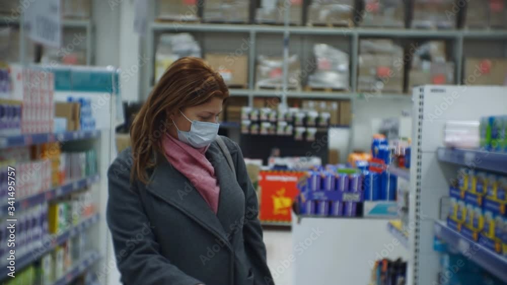 Middle-aged woman in a medical mask makes purchases. Middle-aged woman in a medical mask makes purchases.
