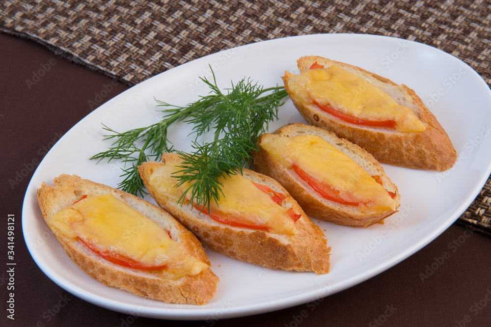 Hot sandwiches. Fried slices of a white baguette with a crispy crust with slices of tomato and cheese, decorated with dill Hot sandwiches. Fried slices of a white baguette with a crispy crust with slices of tomato and cheese, decorated with dill