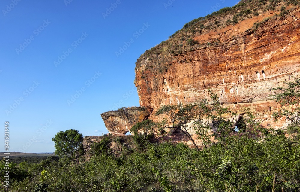Colorful arenite rock wall, contrasting with green vegetations and blue sky in Pedra furada tourist attraction, Jalapao, Brazil.