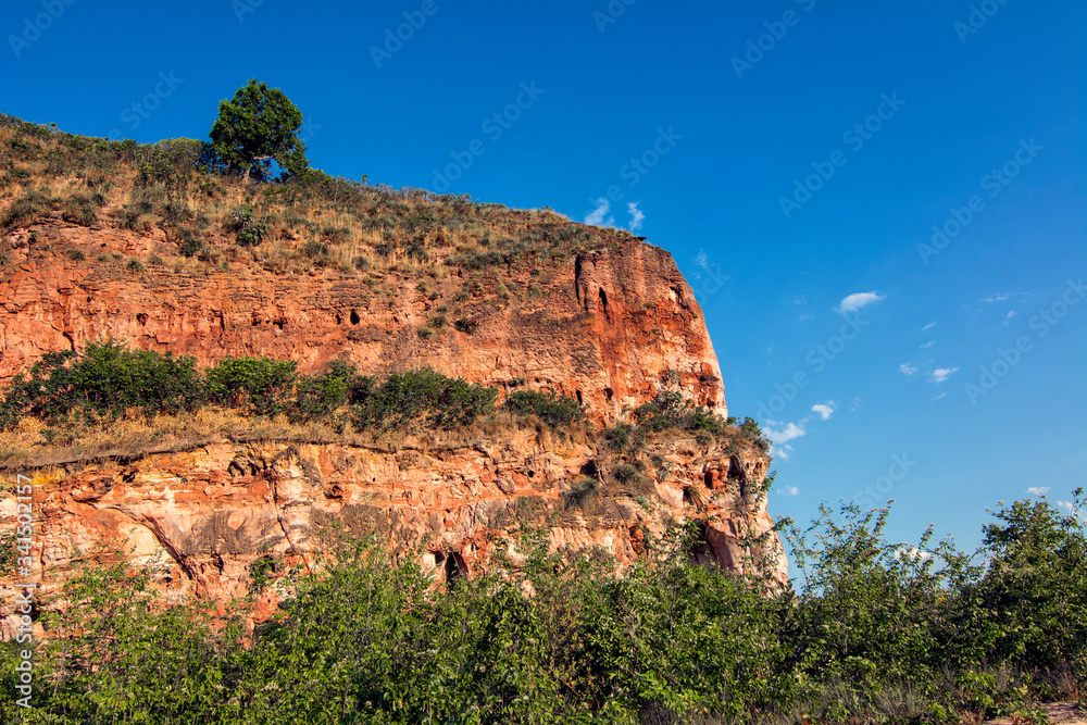 Colorful arenite rock wall, contrasting with green vegetations and blue sky in Pedra furada tourist attraction, Jalapao, Brazil.