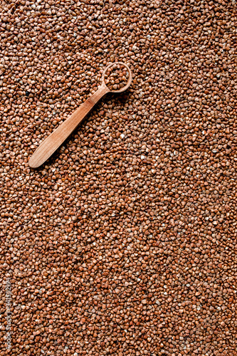 Buckwheat texture. Wooden spoon of roasted buckwheat on buckwheat groat jar background, gluten free ancient grain for healthy diet, selective focus. Coronavirus food supplies. background. top view. photo