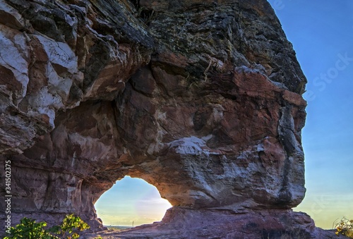 Sunset view through the rock, colorful arenite, contrasting with green vegetations and blue sky in Pedra furada tourist attraction, Jalapao, Brazil.