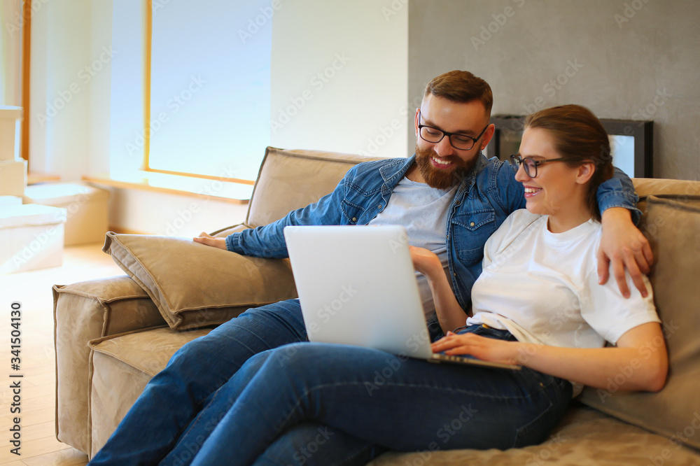 Cheerful couple searching something on laptop at home Cheerful couple searching something on laptop at home
