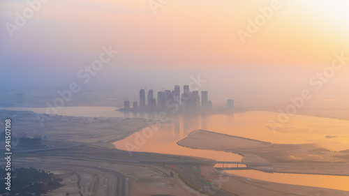 Aerial panoramic view of Dubai skyline in sunrise haze light from highest rooftop, UAE.