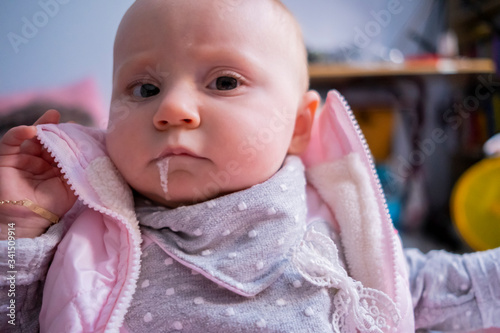 Close-up portrait of cute baby sitting in the baby walker and vomiting milk