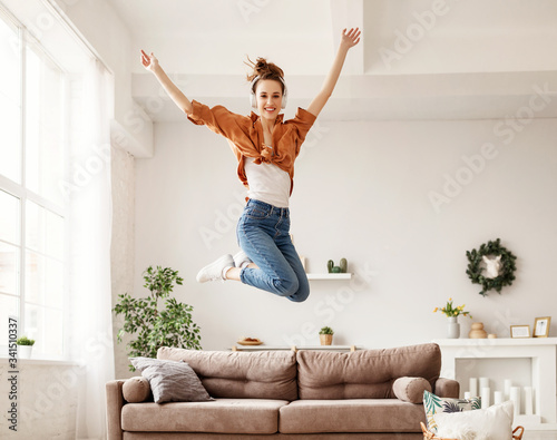 Excited millennial woman listening to music and having fum at home.