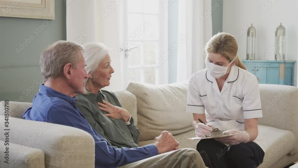 Female doctor wearing face mask makes home visit to senior couple for medical check during covid-19 lockdown - shot in slow motion Female doctor wearing face mask makes home visit to senior couple for medical check during covid-19 lockdown - shot in slow motion