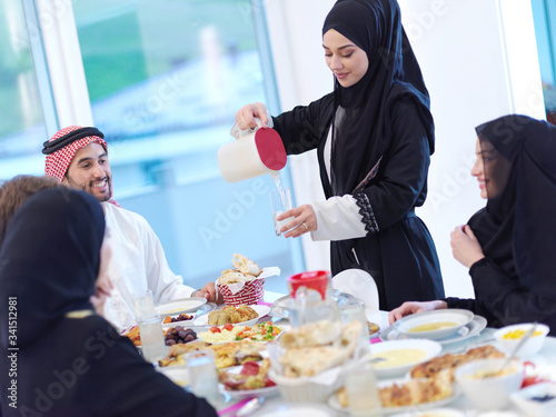 Muslim family having Iftar dinner drinking water to break feast