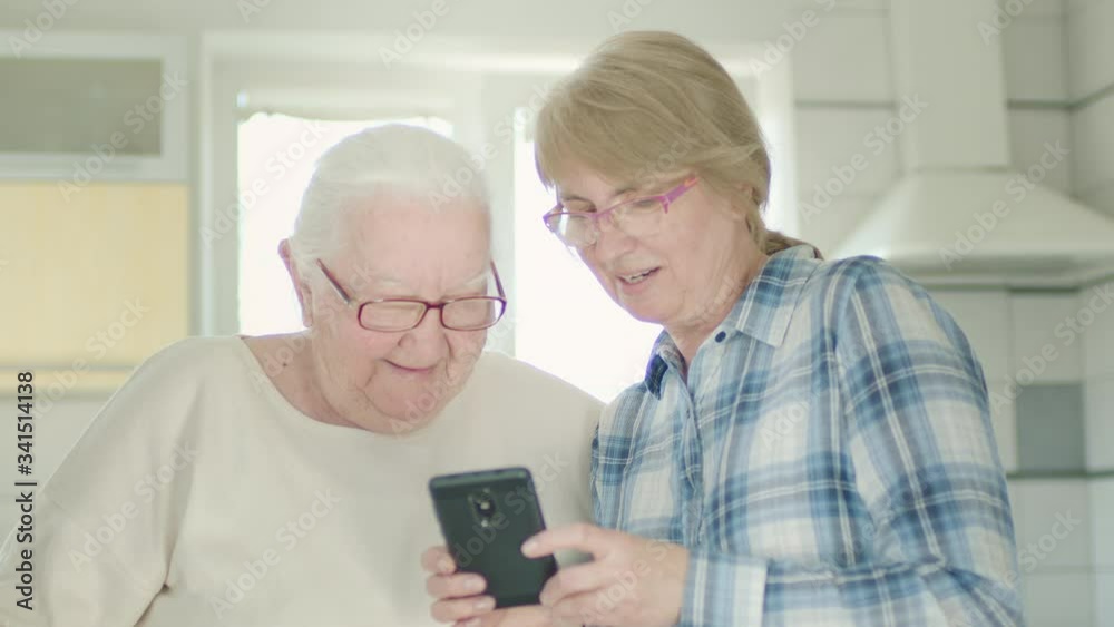 Portrait Of Two Women. Daughter Showing Something To Her Old Mom On Her Cellphone. Portrait Of Two Women. Daughter Showing Something To Her Old Mom On Her Cellphone.