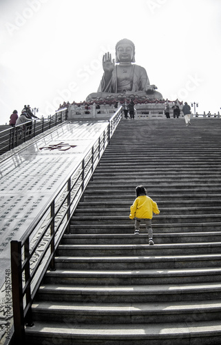 The Nanshan bronze Buddha stairway. A little girls starting the climb. Desatured colors, except from the girls yellow jacket. Worlds largest bronze Buddha, in Nanshan tourist area, China.  photo