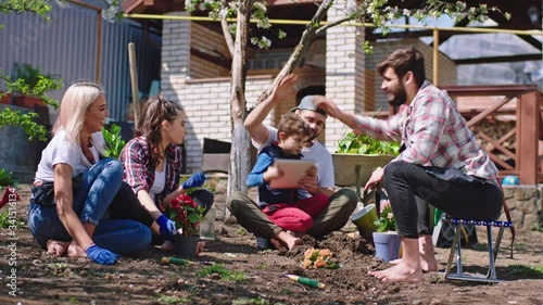 Wallpaper Mural Sunny day for group of friends in the garden planting some flowers feeling happy and relaxed they enjoying the time at fresh air small boy with his dad take a tablet to play a game while others are Torontodigital.ca
