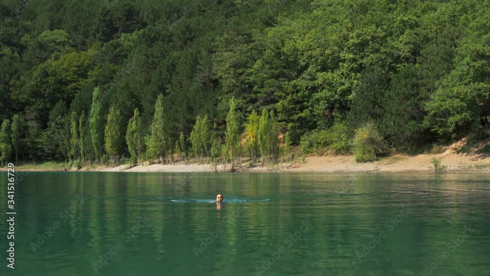 young woman swimming in beautiful mountain lake with clear blue water on woods background. spa relax resort traveling summer vacation young woman swimming in beautiful mountain lake with clear blue water on woods background. spa relax resort traveling summer vacation