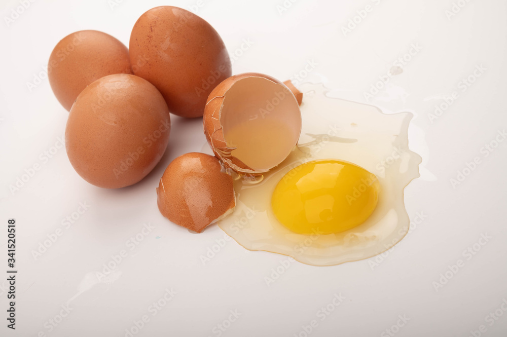 A broken chicken egg and scattered eggs on a white background. Close up. A broken chicken egg and scattered eggs on a white background. Close up.