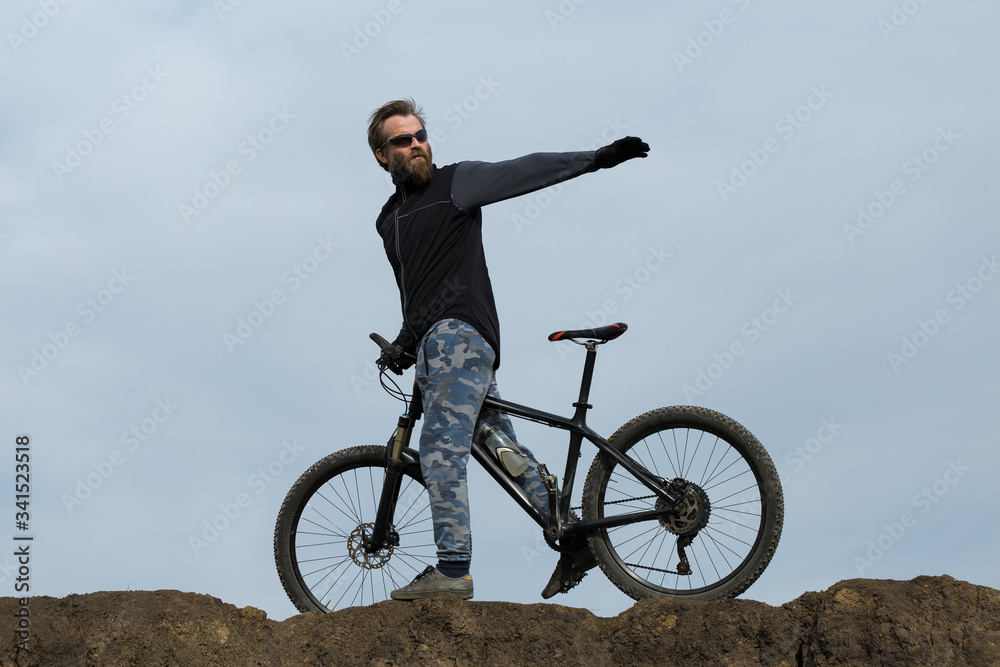 Sports brutal bearded guy on a modern mountain bike. Beautiful view from the mountain. Panoramic view for banner. Sports brutal bearded guy on a modern mountain bike. Beautiful view from the mountain. Panoramic view for banner.