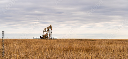 Oil Well Pump Jack pumping crude oil for fossil fuel energy. American Petroleum Oil and Gas Industry equipment extracting from a prairie in the United States of America.