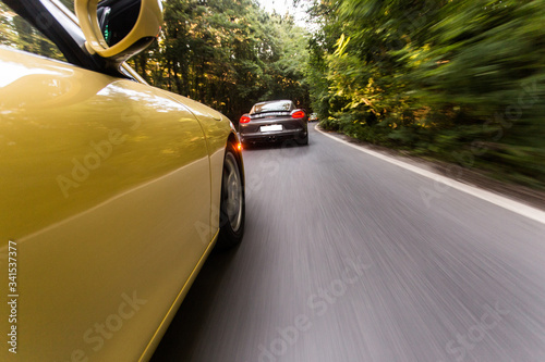 Black cars driving on the transit freeway in the sunset, yellow car following