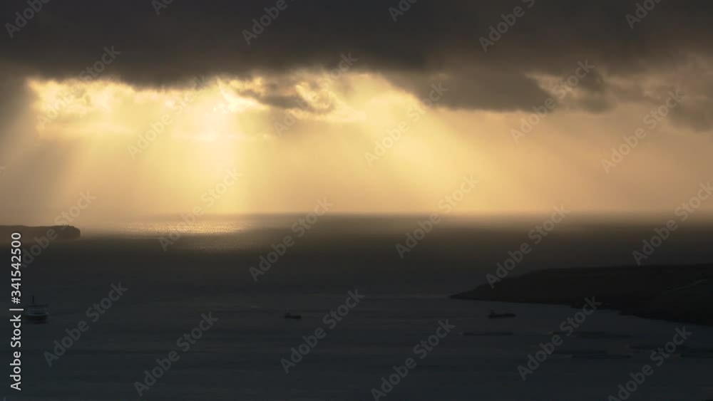 Rays of sun light shining from above moving clouds to the sea Rays of sun light shining from above moving clouds to the sea