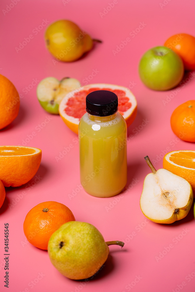 Fruit is scattered around the juice bottle on a pink background Fruit is scattered around the juice bottle on a pink background