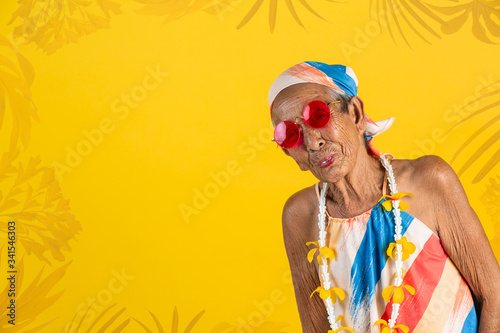 Funny grandmother set in stodio, on color theme, yellow background, grandmother is getting to go out for festival. photo