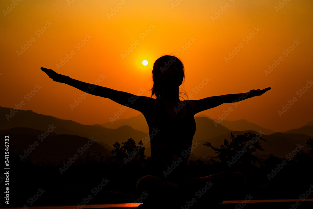 Silhouette - Yoga girl is practicing on the rooftop while sunset.