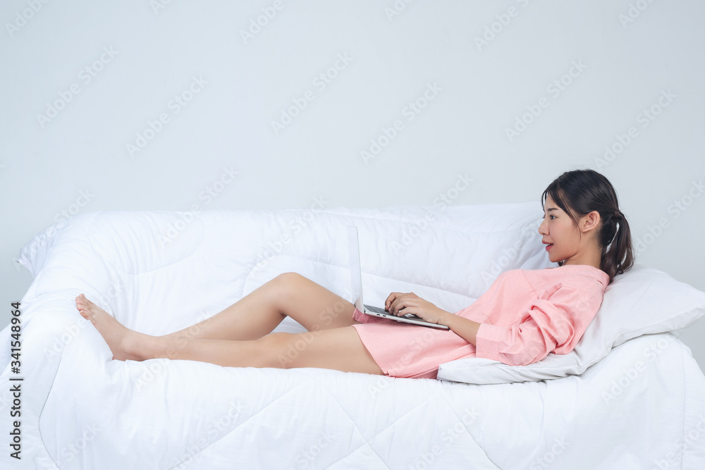 Freelance, working at home -Young woman is working while laying on the sofa at home. - obrazy, fototapety, plakaty 